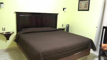 Un dormitorio con una cama grande, una mesita de noche, una lámpara de pared y un cuadro en la pared.