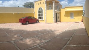 Um carro vermelho estacionado na entrada de um prédio amarelo com um pátio de lajes de pedra.