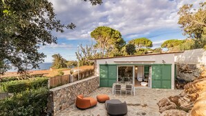A patio with outdoor seating, a stone wall, and a view of the sea. - Appartamento Mare di Spartaia (Marciana)