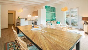 A spacious living area with a wooden dining table, wicker chairs, and a sofa with teal cushions. - Appartamento Mare di Spartaia (Marciana)