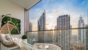 A balcony with two white wicker chairs, a hanging chair, and a potted plant.