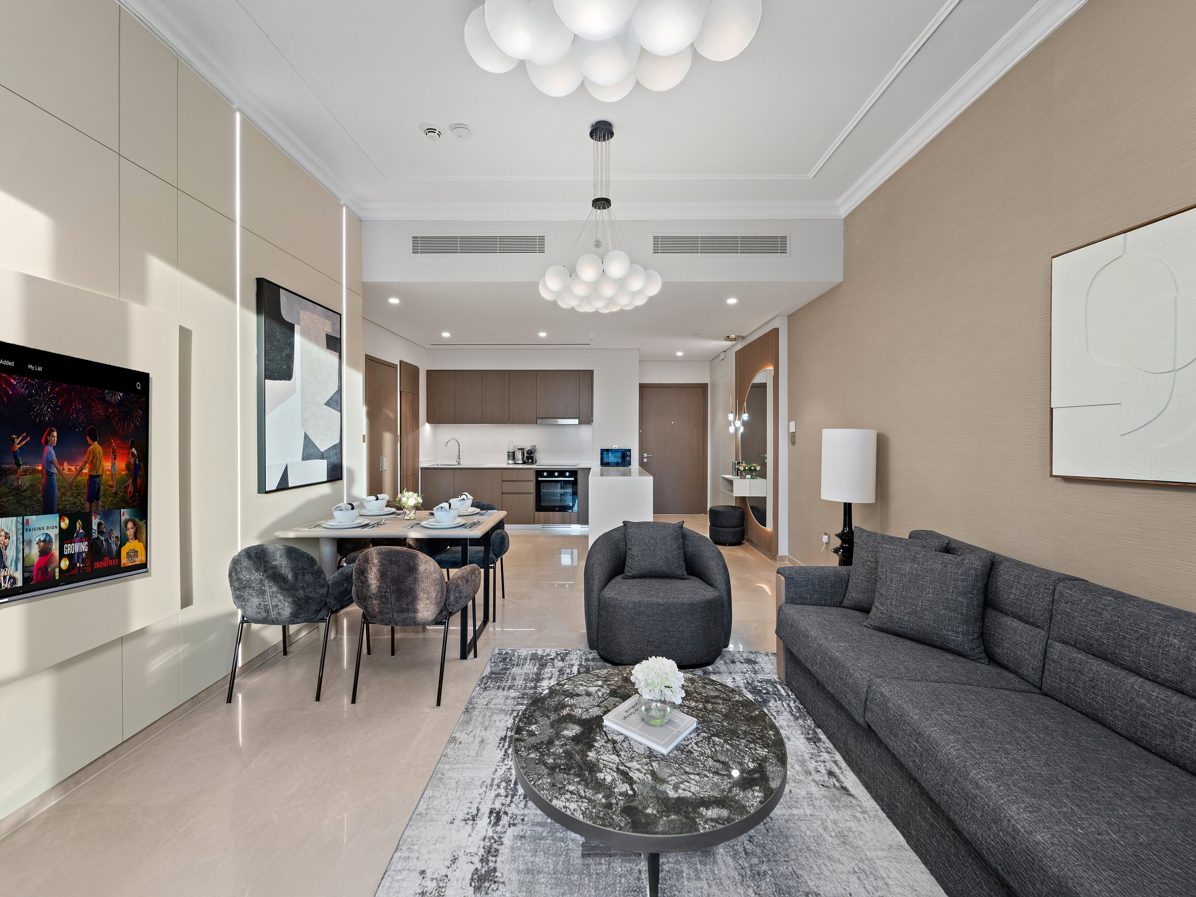A modern living room with a grey sofa, a round coffee table, and a dining area with a table set for four.