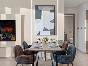 A modern dining area with a large abstract painting, a table set for six, and a variety of chairs.