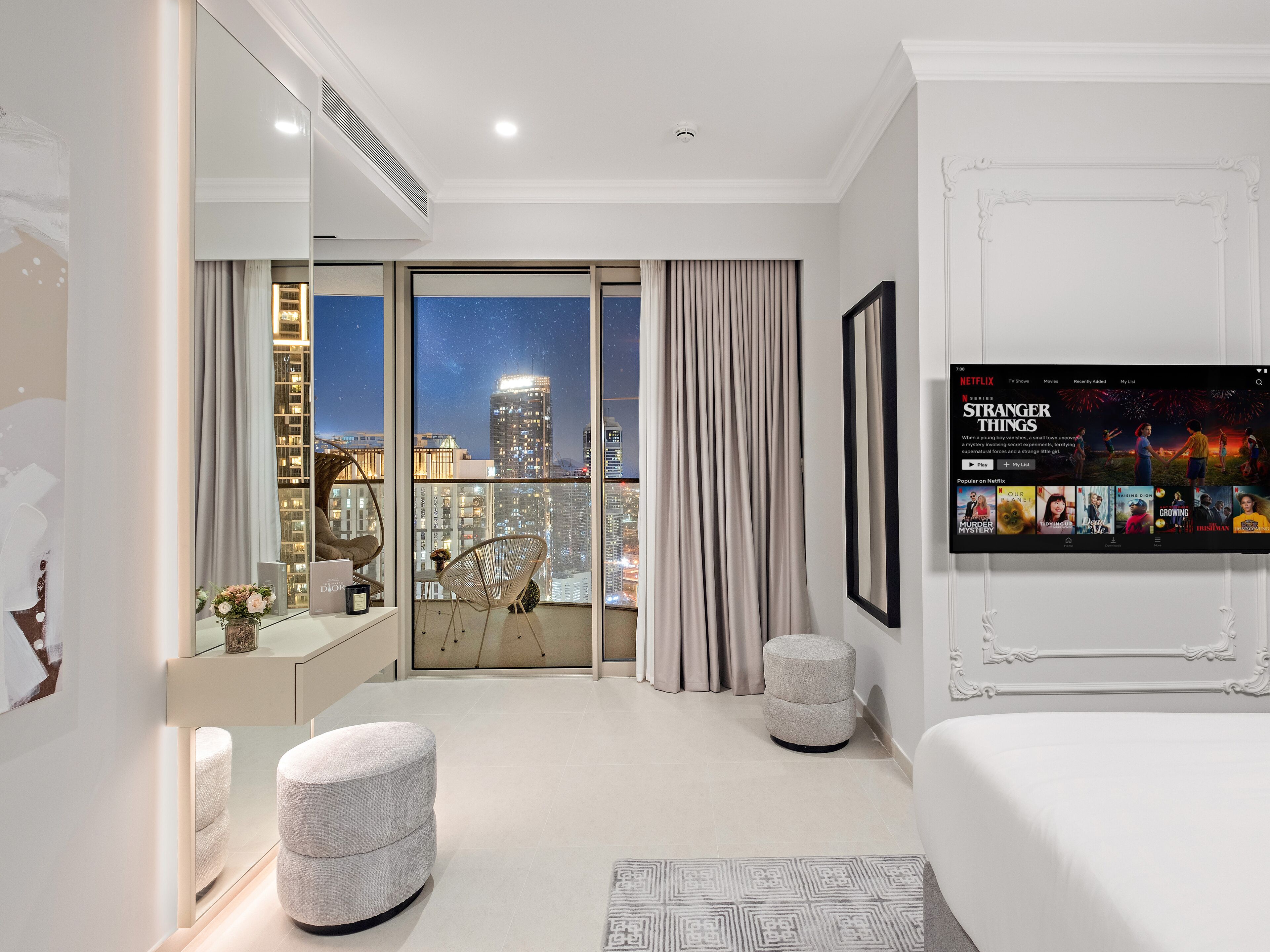 Une chambre d’hôtel moderne dotée d’une grande fenêtre donnant sur la ville, d’un téléviseur à écran plat et d’un décor minimaliste.