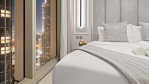 A modern hotel room with a large bed, a view of a city skyline, and a window with a view of a tall building.