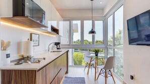 A modern kitchen with a large island, a dining area with a glass table and chairs, and a TV mounted on the wall. - Altamar Canal View Condos (Nuevo Nayarit)