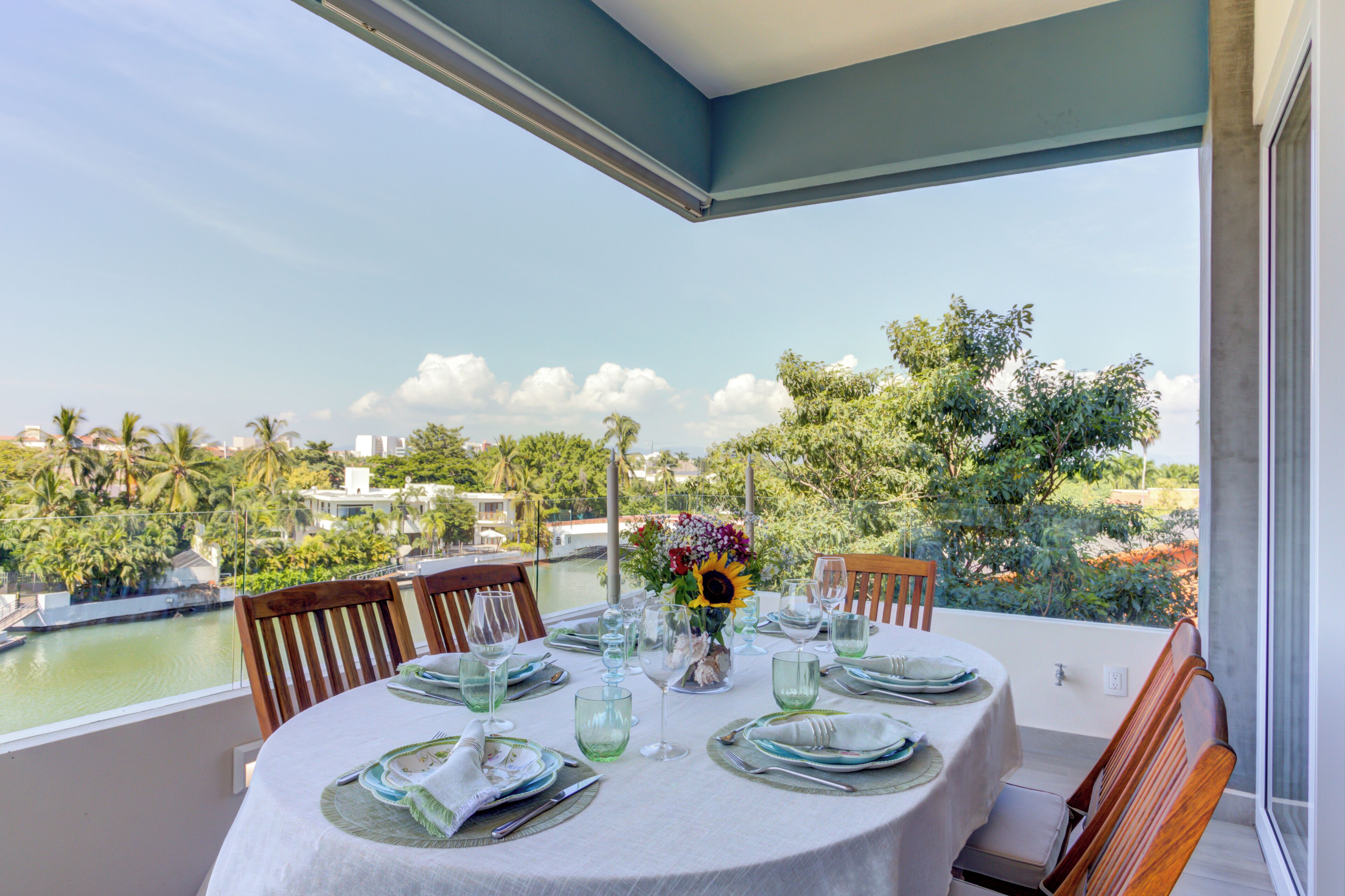 A round table set for dining with a view of a body of water and greenery.