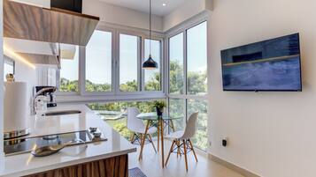 Een moderne keuken met een groot raam, een eethoek met twee stoelen en een tv aan de muur.