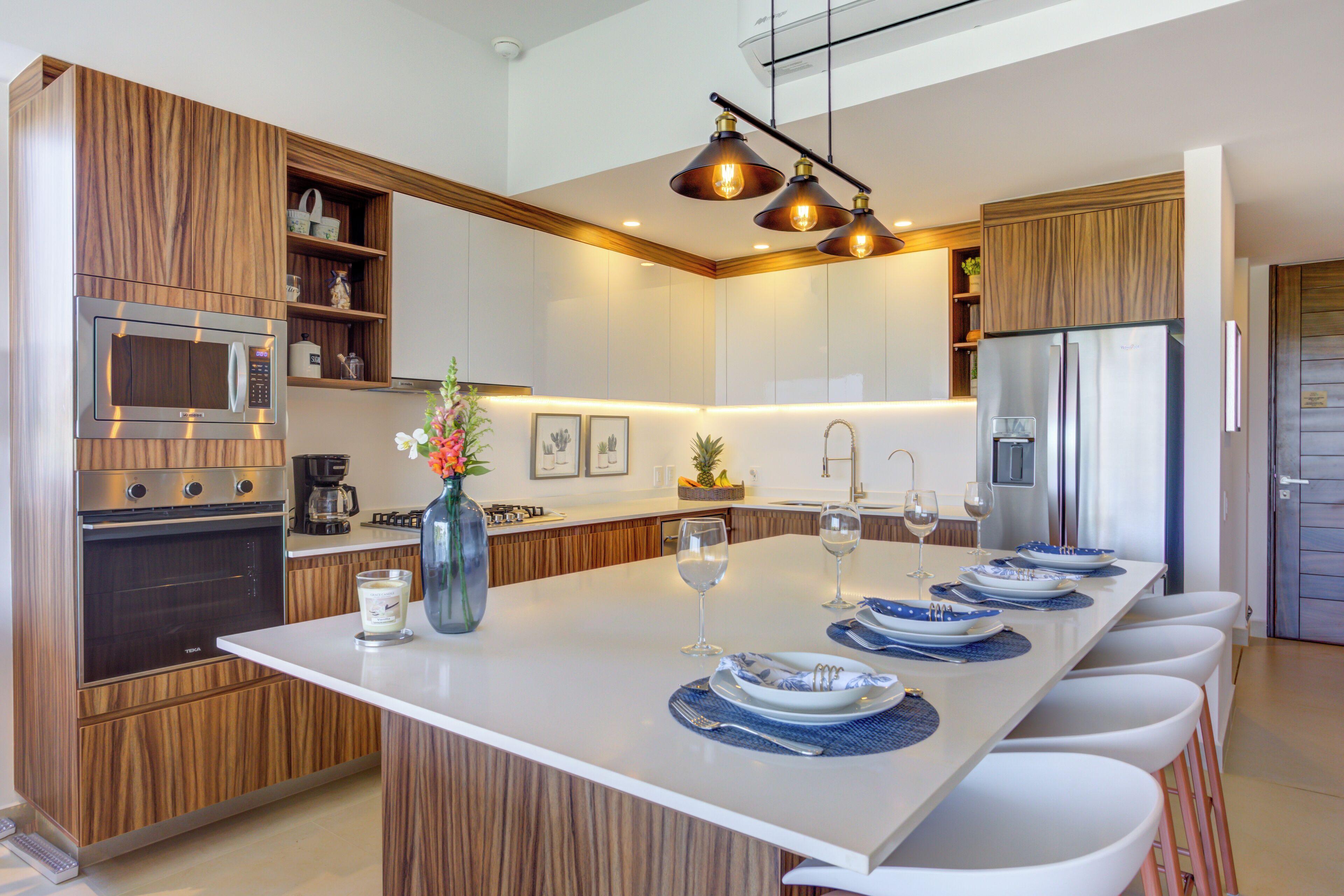 A modern kitchen with wooden cabinetry, stainless steel appliances, and a central island with bar seating.