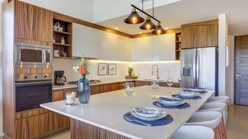 A modern kitchen with wooden cabinetry, stainless steel appliances, and a central island with bar seating.