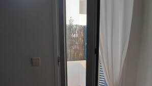 An open sliding glass door leading to a balcony with a view of a fence and a building. - Charming 2BR/2BA apartment with pool - 32 nights minimum! (El Pilar de la Mola)