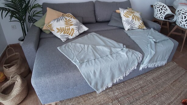 A grey sofa with patterned pillows and a light blue throw blanket. - Charming 2BR/2BA apartment with pool - 32 nights minimum! (El Pilar de la Mola)