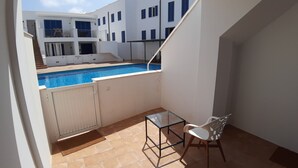 A balcony with a pool, a glass table, and a chair. - Charming 2BR/2BA apartment with pool - 32 nights minimum! (El Pilar de la Mola)