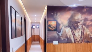 A hotel hallway with wooden paneling, framed pictures on the walls, and a mural depicting a person with a mountainous background. - Hotel Shri Sai Deluxe - 1 Min from Adarsh Nagar Metro | Couple, Business, and Family Friendly (New Delhi)