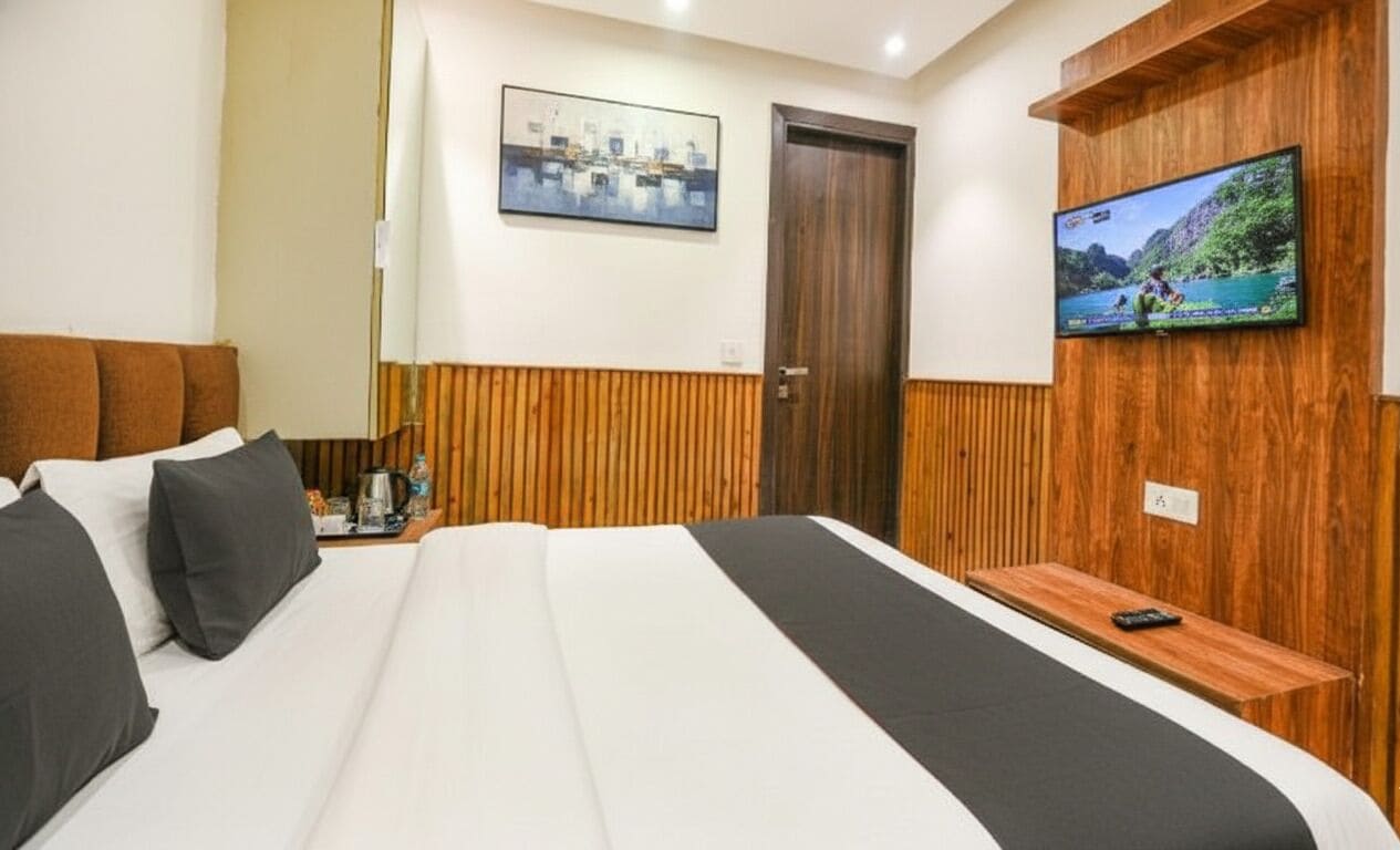 A hotel room with a large bed, a television mounted on the wall, and a wooden panel design on the walls.