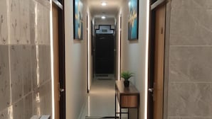 A modern hallway with a tiled floor, a bench, a small table with a plant, and a blue chair. - Hotel Shri Sai Deluxe - 1 Min from Adarsh Nagar Metro | Couple, Business, and Family Friendly (New Delhi)
