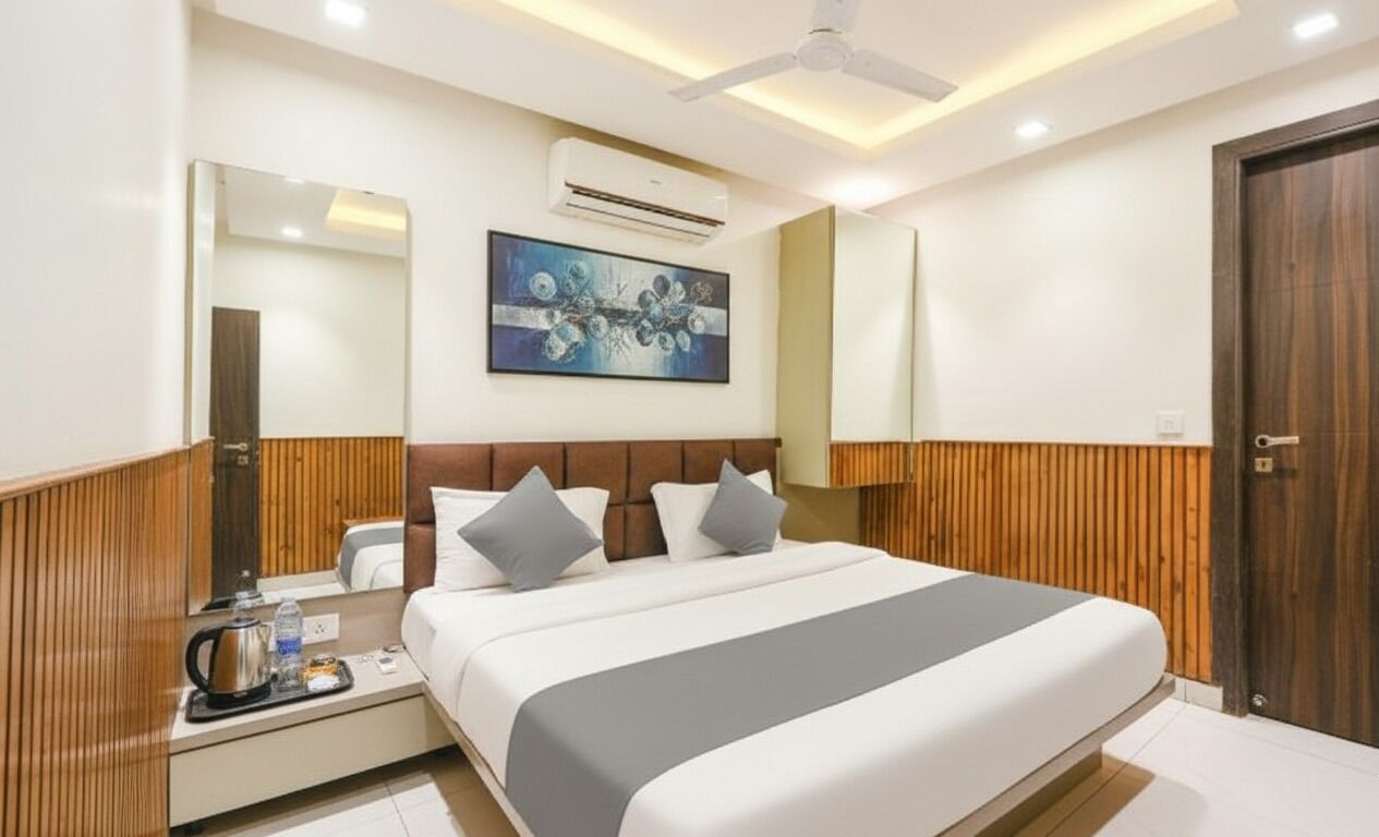 A modern hotel room with a large bed, wooden paneling on the walls, a ceiling fan, an air conditioning unit, a painting on the wall, and a wooden door.