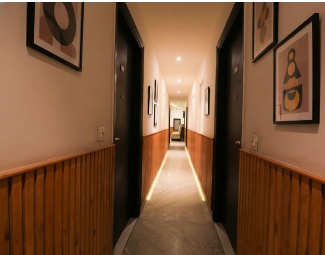 A hallway with wooden paneling, framed artwork on the walls, and a carpeted floor.