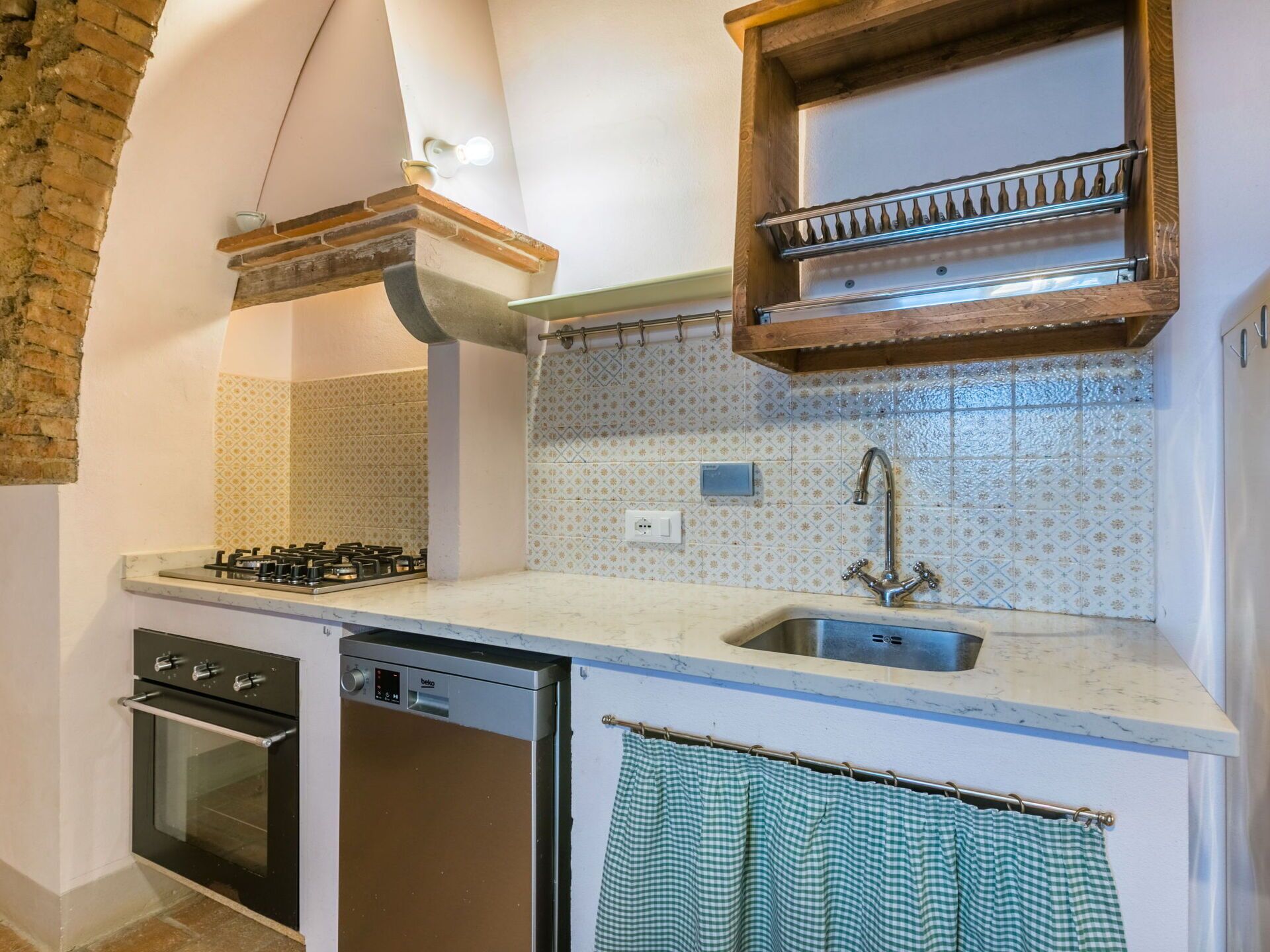 A compact kitchen with a gas stove, dishwasher, and a sink with a faucet.