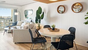 A modern living room with a sofa, chairs, a round table, and a large plant. - 68th St Oceanfront Condo with Pool (Ocean City)