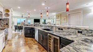 Una cocina moderna con encimeras de granito, electrodomésticos de acero inoxidable e iluminación colgante.