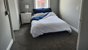 Une chambre à coucher avec un lit, une table de chevet et une fenêtre donnant sur un immeuble en briques.