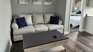 Un salon moderne avec un canapé beige, une petite table et trois tableaux abstraits accrochés au mur.