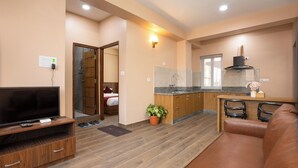A modern living room with a TV, wooden entertainment unit, and a leather sofa. - Mandevilla Home (Lalitpur)