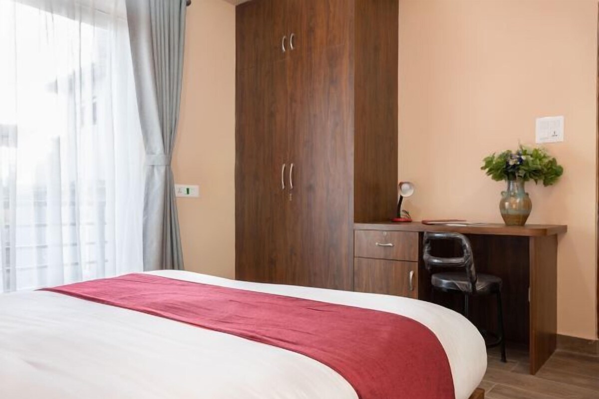 A bedroom with a bed, a desk, and a chair.