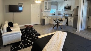 A modern apartment with a living room, dining area, kitchenette, and bedroom.