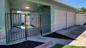 A residential garage with a gated entrance, a covered porch, and a driveway leading to a garage door.
