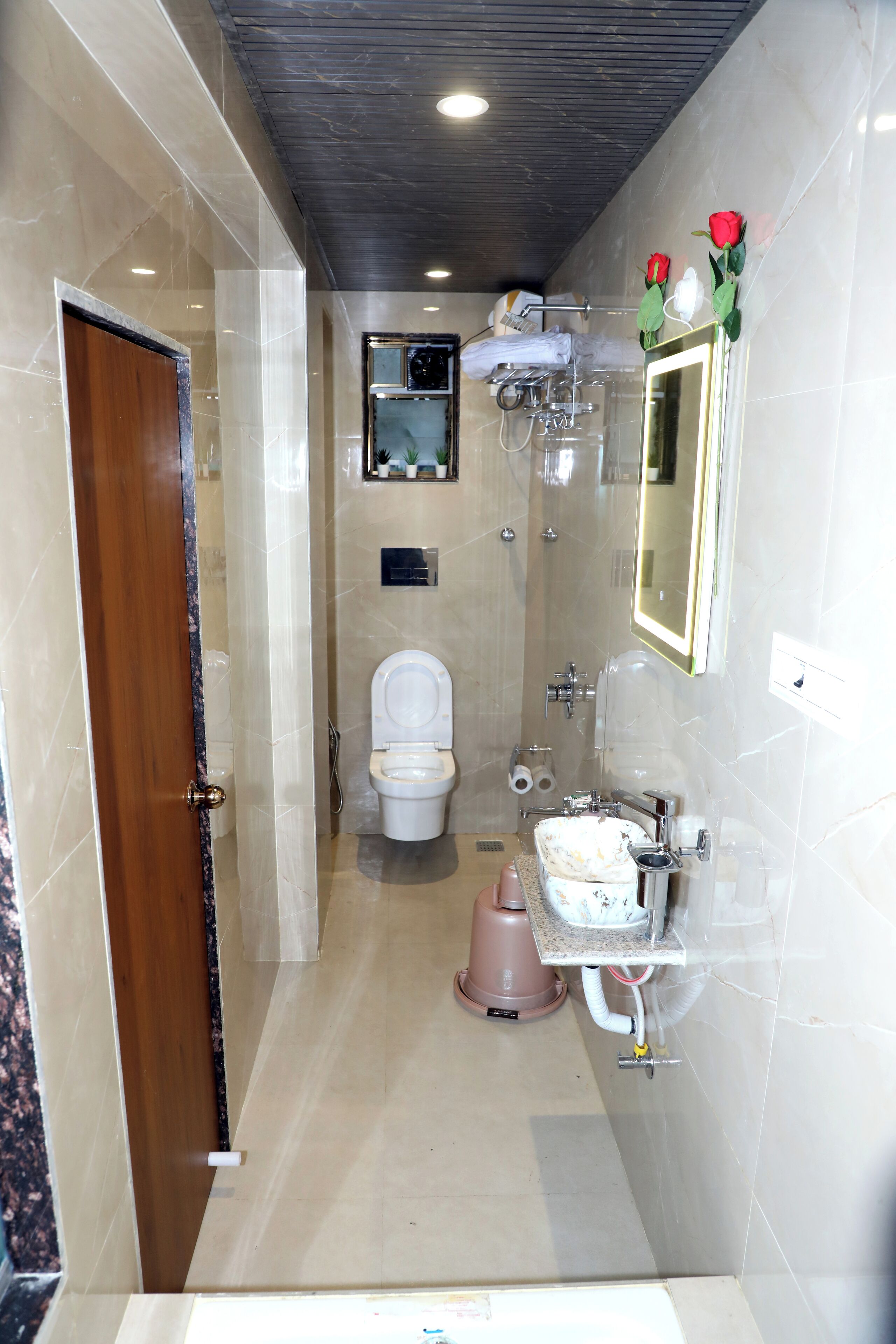 A bathroom with a toilet, sink, shower, and a mirror.