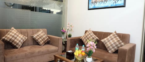 A living room with two brown sofas, a glass coffee table, and a painting of horses on the wall.