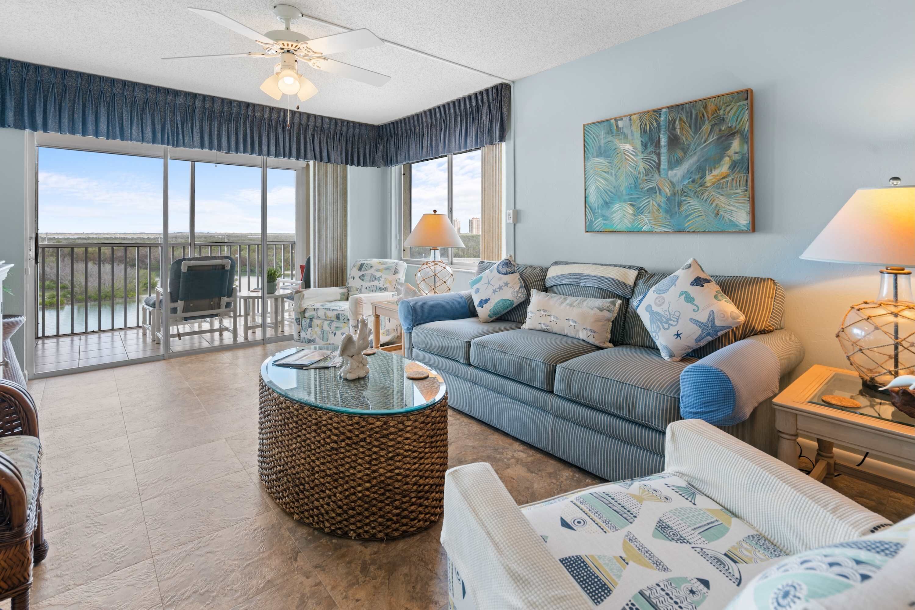 A spacious living room with a large window, a ceiling fan, and a view of the outdoors.