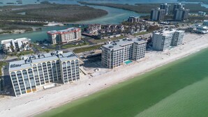 Un hotel frente al mar con varias construcciones, una playa y un puerto deportivo.