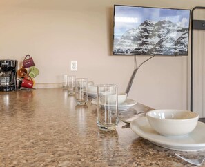 A kitchen counter with a coffee maker, a set of glasses, and a bowl on a plate. - Baby Bear Cabin (West Yellowstone)