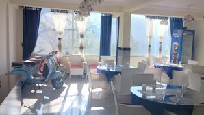 A dining area with wicker furniture, a scooter, and a Pepsi refrigerator. - Hotel Copacabana (Abbottabad)