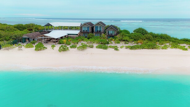 A beachfront property with multiple buildings, including a large house with a balcony and a smaller structure with a roof. - Araaik Beach Village (Hoarafushi)