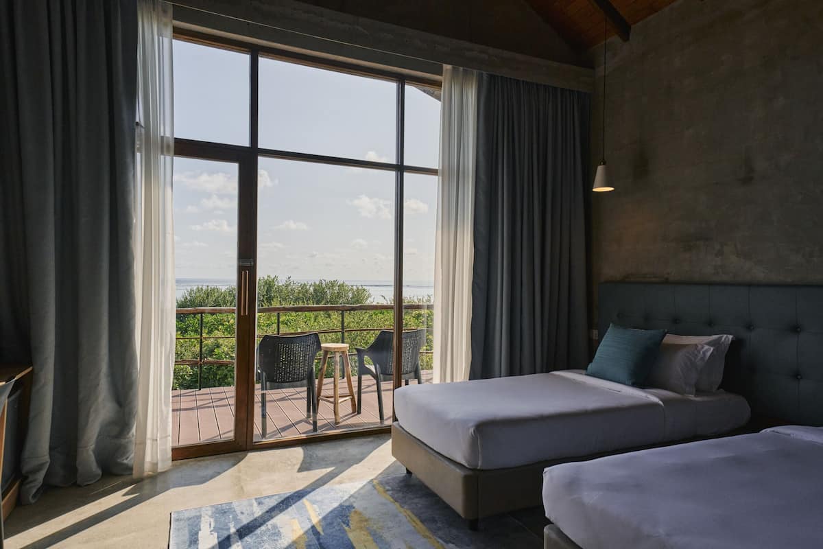 Quarto de hotel com varanda, cama e vista para o mar.