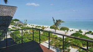 A beach view from a balcony with a railing, a wooden deck, and tropical vegetation. - Araaik Beach Village (Hoarafushi)
