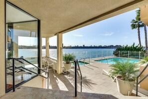 A poolside area with a view of the sea, outdoor seating, and a staircase leading to an upper level. - Waterfront Condo w/ Dock Access in Carlsbad! (Carlsbad)