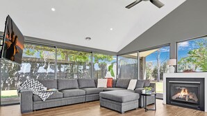Una sala de estar moderna con un sofá seccional, una chimenea y ventanas amplias que ofrecen vistas al exterior.