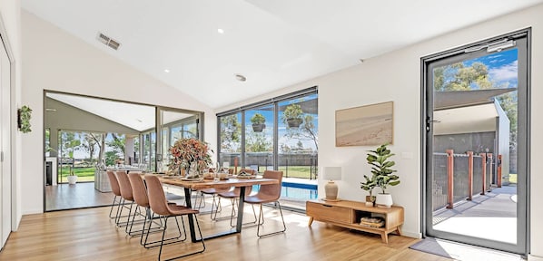 A modern dining area with a large table, chairs, and a view of the outdoors.
