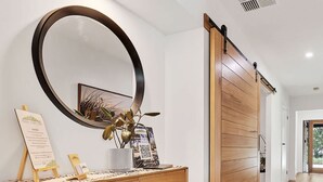 Un interior moderno con una consola de madera, un espejo redondo grande y una puerta corredera.