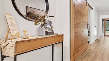 A modern interior with a wooden console table, a large round mirror, and a sliding door.