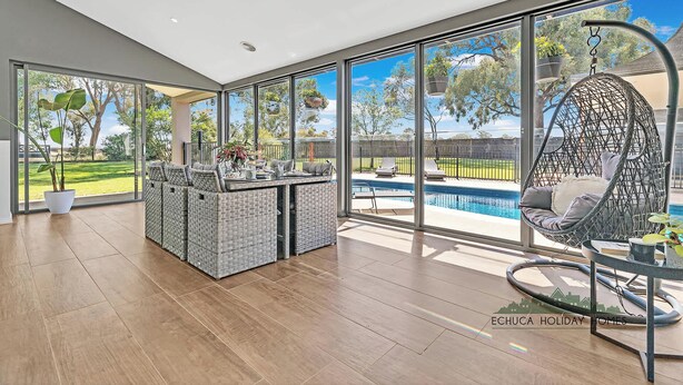 Un patio amplio con piscina, ventanas grandes y mobiliario de exterior.
