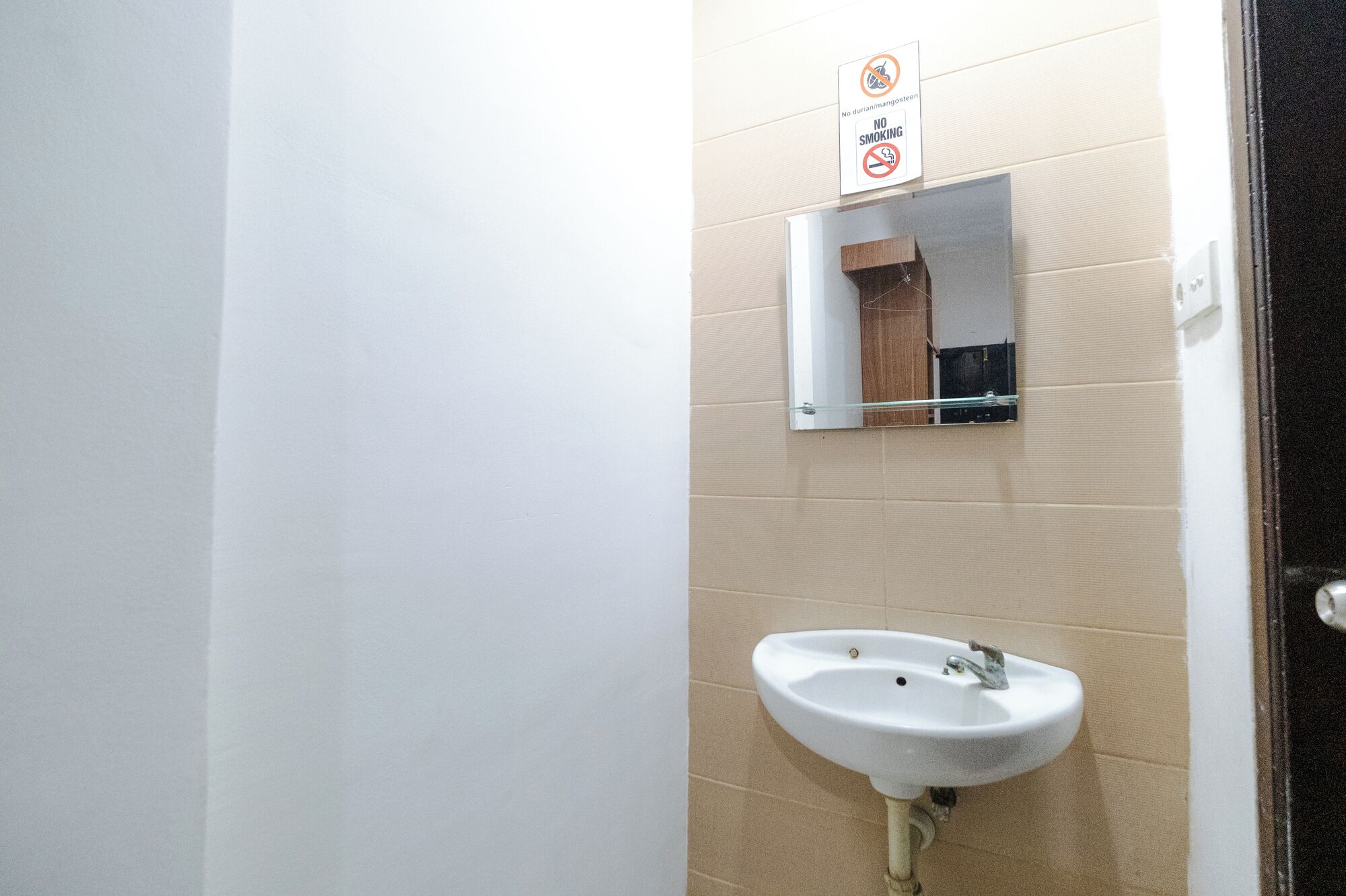 A bathroom with a white sink, a mirror, and a 'No Smoking' sign.