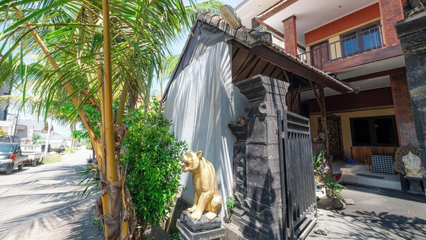 A building with a stone lion statue, a metal gate, and a palm tree. - Apartment Kak Okoh  (Munggu)