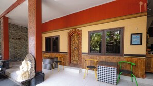 A restaurant with a checkered table and chairs, a statue, and a decorative door. - Apartment Kak Okoh  (Munggu)