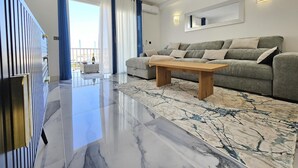 Ein modernes Wohnzimmer mit grauem Sofa, einem Holztisch und einem Teppich mit Marmoroptik.